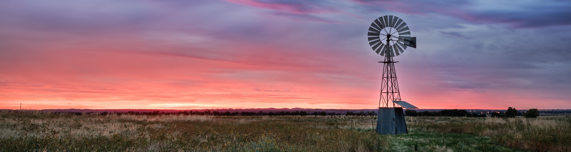 Old windmill sitting in over field at sunrise